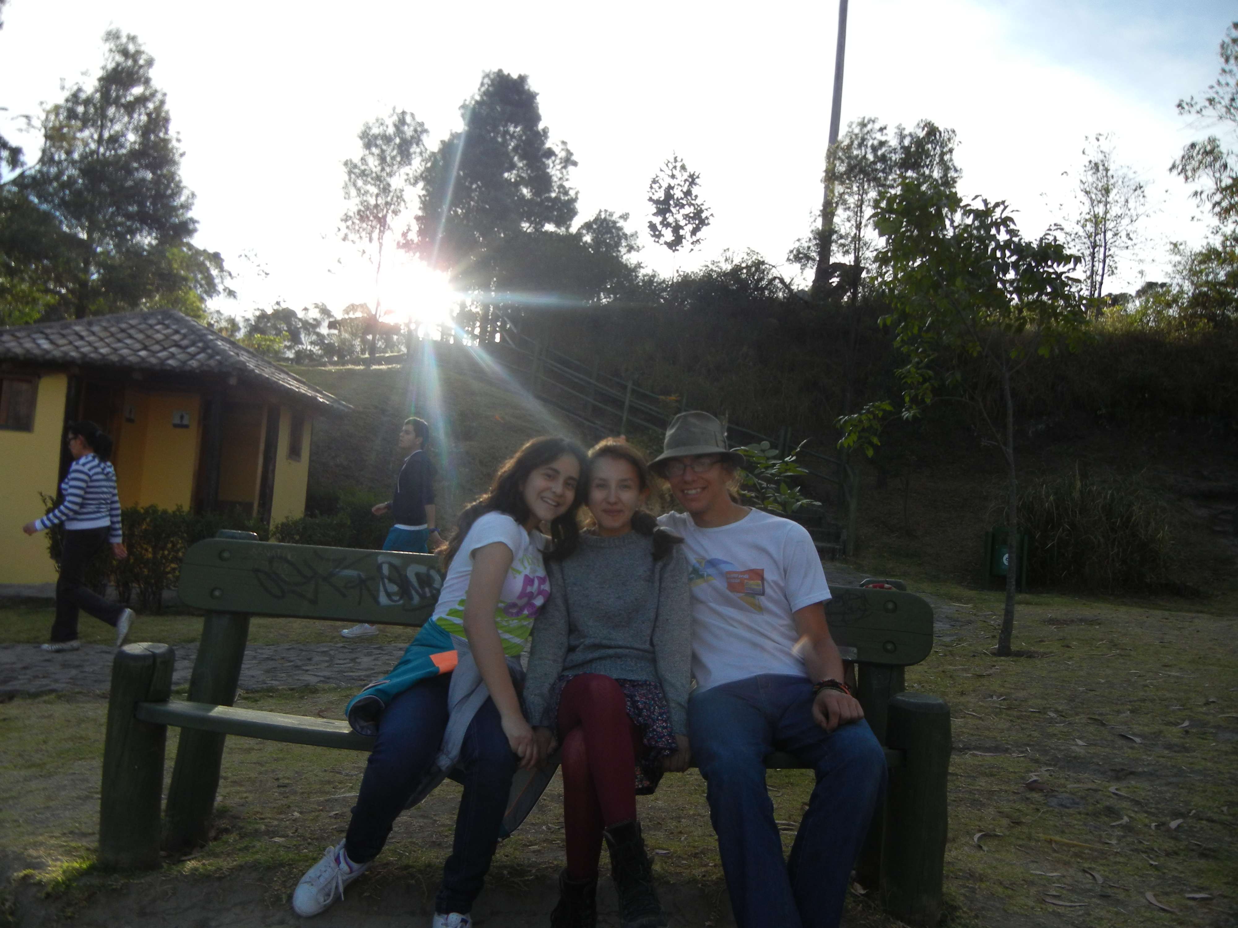 Three people on a bench in front of a sunset